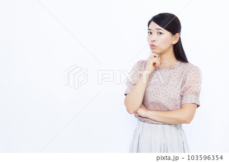白い背景の前で真剣に悩んでいる30代の女性 103596354