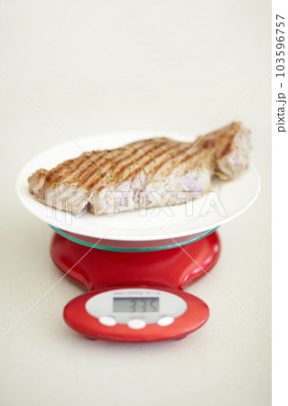 Weighing dinner, scale and measuring beef for calories, nutritional value and protein on a plate. Healthy meat, measurement and a steak for dietary portion for a balanced diet on a table for lunch 103596757