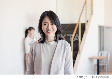 笑顔でオフィスを歩く女性経営者 103596880