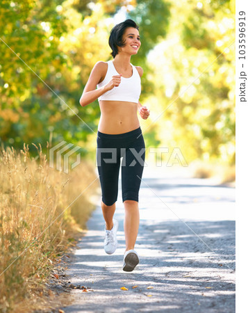 Woman is running in road, sport and fitness outdoor with fit body, healthy and active person. Cardio, exercise and training for race, young female runner in nature with workout for health 103596919