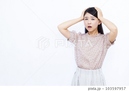 白い背景の前で頭を抱えて驚く30代の女性 103597957