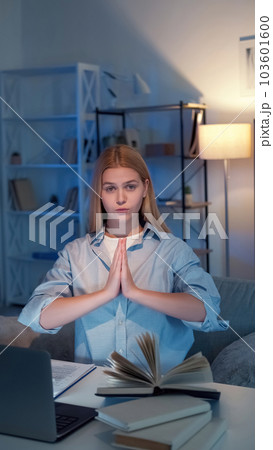 Praying gesture. Peaceful woman. Perfect student. Calm lady ready for exam holding hands together sitting with books laptop in light room interior. Praying gesture. Peaceful woman. Perfect student. Calm lady ready for exam holding hands together sitting with books laptop in light room interior. 103601600
