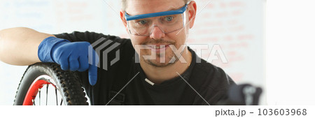 Professional mechanic repairs bicycle in modern workshop and records video 103603968