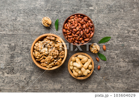 Walnut kernel halves with peanut, in a wooden bowl. Close-up, from above on colored background. Healthy eating groundnut concept. Super foods with copy space Walnut kernel halves with peanut, in a wooden bowl. Close-up, from above on colored background. Healthy eating groundnut concept. Super foods with copy space 103604029