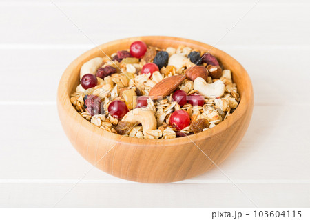 Cooking a wholesome breakfast. Granola with Various dried fruits and nuts in a bowl. The concept of a healthy dessert. Flat lay, top view with copy space Cooking a wholesome breakfast. Granola with Various dried fruits and nuts in a bowl. The concept of a healthy dessert. Flat lay, top view with copy space 103604115