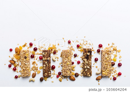 Various granola bars on table background. Cereal granola bars. Superfood breakfast bars with oats, nuts and berries, close up. Superfood concept Various granola bars on table background. Cereal granola bars. Superfood breakfast bars with oats, nuts and berries, close up. Superfood concept 103604204