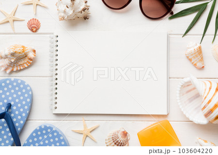 Blank writing book with summer beach accessories on background, copy space. Flat lay with copy space Blank writing book with summer beach accessories on background, copy space. Flat lay with copy space 103604220