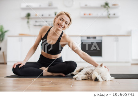 Yogini stroking dog during break in yoga session at home 103605743