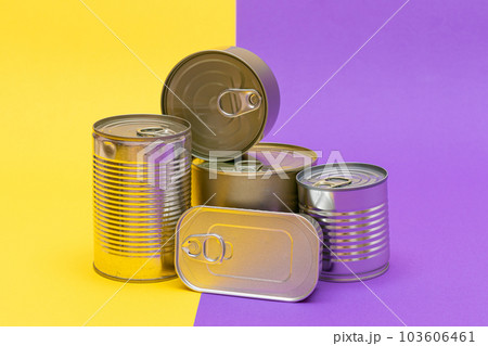 A Group of Stacked Tin Cans with Blank Edges on Split Yellow and Violet Background A Group of Stacked Tin Cans with Blank Edges on Split Yellow and Violet Background 103606461