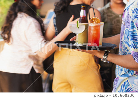 Waiter serving cocktail for group of people celebrating. 103608230