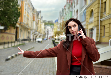 business Woman on the street talking on the phone while stopping a cab. business Woman on the street talking on the phone while stopping a cab. 103611723