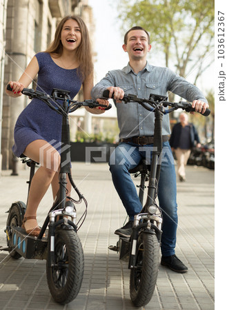 young couple of girl and guy enjoy a ride on electric scooters 103612367