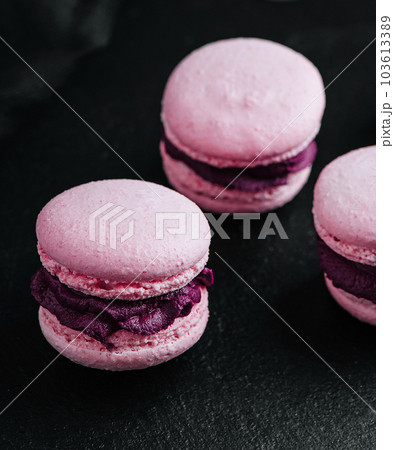 Pink macarons with chocolate filling on black stone 103613389