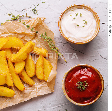 Baked fried potatoes with red and white sauces 103614097