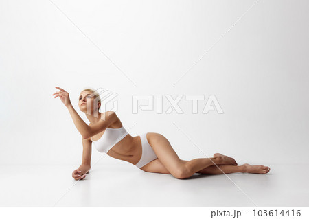 Tenderness. Portrait of young attractive woman with slim, fit body shape posing in underwear against grey studio background 103614416