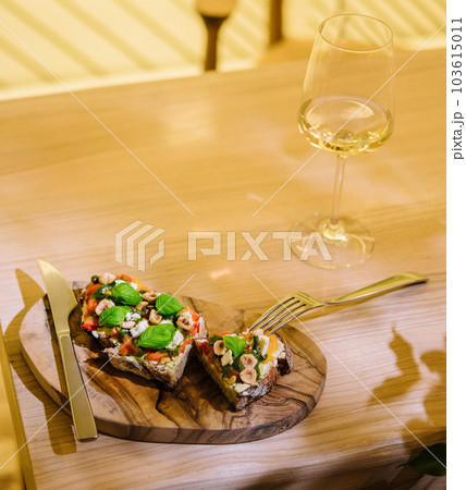 Glass of wine and bruschetta with pesto sauce, feta cheese, tomatoes and basil 103615011