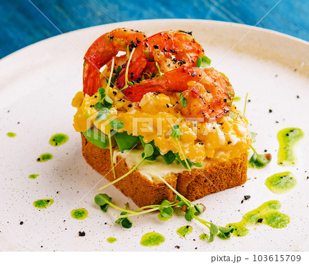 Scrambled eggs with avocado and shrimps on plate 103615709