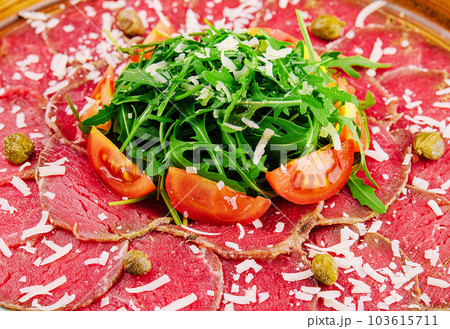 Beef carpaccio with capers, parmesan, arugula and tomatoes 103615711