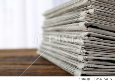 Stack of newspapers on wooden table, space for text. Journalist's work 103615815