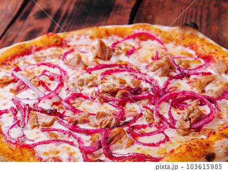 Pizza with tuna and red onion on wooden cutting board Pizza with tuna and red onion on wooden cutting board 103615985