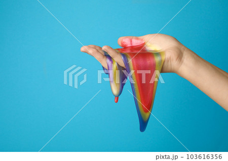 Woman playing with colorful slime on light blue background, closeup. Antistress toy 103616356