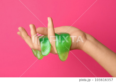 Woman playing with green slime on pink background, closeup. Antistress toy 103616357