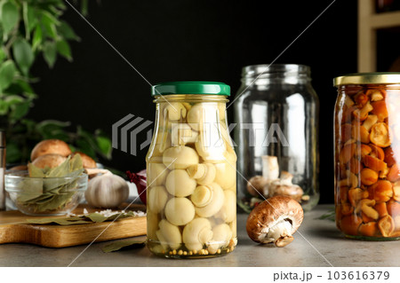 Glass jars of pickled mushrooms on light grey table Glass jars of pickled mushrooms on light grey table 103616379