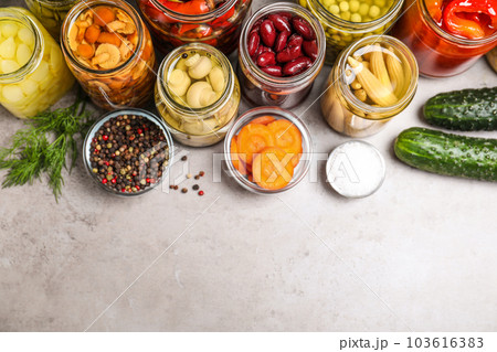 Glass jars with different pickled vegetables on grey table, flat lay. Space for text 103616383