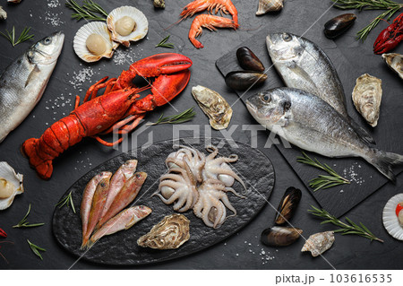 Fresh fish and different seafood on black table, flat lay 103616535