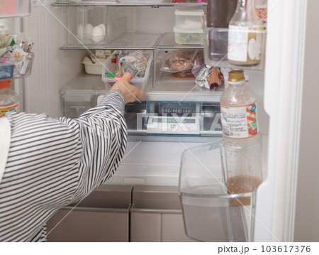 【冷蔵室からトレイを取り出す主婦】 103617376