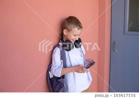 Cute boy playing on the phone. The child goes home from school. 103617558