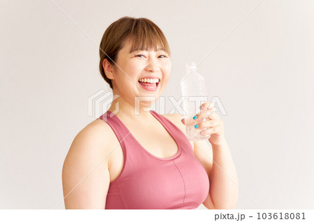 ペットボトルの水を手に持つ笑顔のぽっちゃり女子 プラスサイズモデル エクササイズ ペットボトルの水を手に持つ笑顔のぽっちゃり女子 プラスサイズモデル エクササイズ 103618081