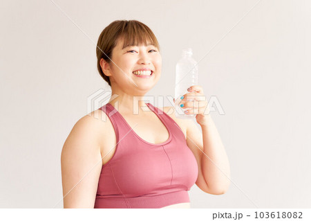 ペットボトルの水を手に持つ笑顔のぽっちゃり女性　プラスサイズモデル　エクササイズ 103618082