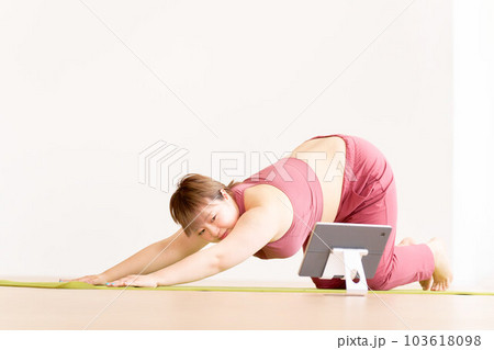 タブレットを見ながらヨガをする豊満な若い女性 プラスサイズモデル イメージ タブレットを見ながらヨガをする豊満な若い女性 プラスサイズモデル イメージ 103618098