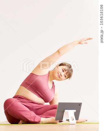 タブレットを見ながらヨガをする豊満な若い女性 プラスサイズモデル イメージ タブレットを見ながらヨガをする豊満な若い女性 プラスサイズモデル イメージ 103618106