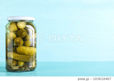 Glass jar of pickles on light blue wooden table. Space for text Glass jar of pickles on light blue wooden table. Space for text 103618467