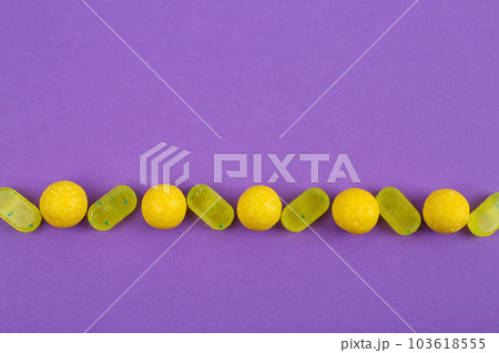 Delicious lemon candies on purple background, flat lay Delicious lemon candies on purple background, flat lay 103618555