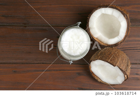 Halves of ripe coconut and organic oil on wooden table, flat lay with space for text. Healthy cooking Halves of ripe coconut and organic oil on wooden table, flat lay with space for text. Healthy cooking 103618714