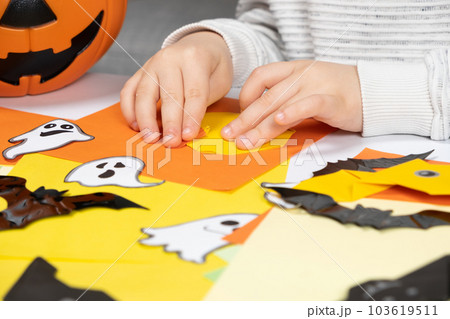 A child creates a pumpkin out of paper. Origami for Halloween, preparation A child creates a pumpkin out of paper. Origami for Halloween, preparation 103619511