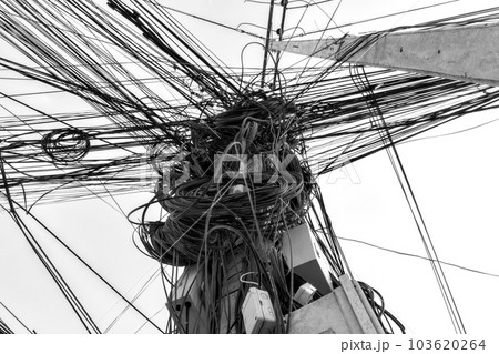 A cluster of wires and cables entangled on a pole, capturing the intricate and chaotic network of Asian power lines. 103620264