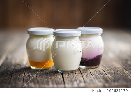 White and fruit yogurt in jar on wooden table. White and fruit yogurt in jar on wooden table. 103621179