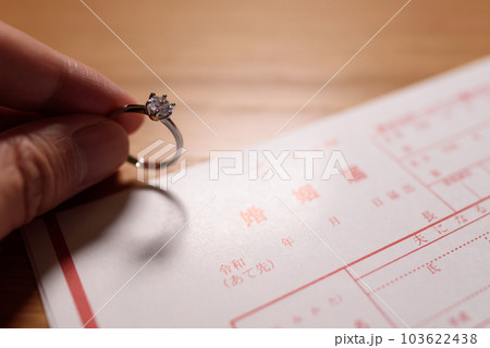 婚姻届と手に持った結婚指輪　婚約指輪　元号令和の書類 103622438