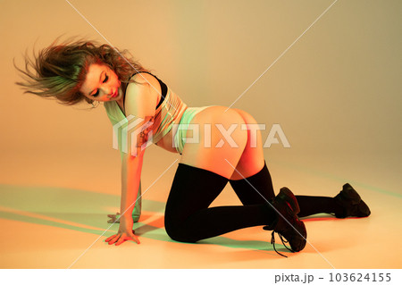 Woman performs flexible movements, twerking body on floor. Hot dance in neon 103624155