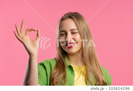 Pretty woman with OKAY sign, ok gesture. Happy lady, correct choice on pink wall 103624286