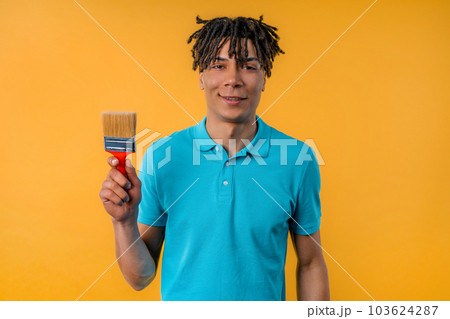 Young african man artist with brush on yellow background. Creative person. 103624287