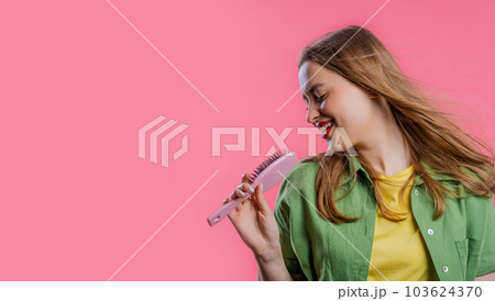 Woman singing, dancing with hair brush instead microphone on pink. Copy space 103624370