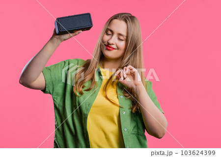 Young woman listening to music by wireless portable speaker modern sound system 103624399