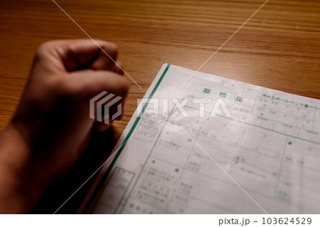 離婚届を前に、拳を握り怒る男性の手　 103624529