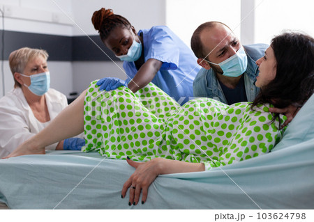 Future mother delivery child in hospital ward, medical team and husband comforting patient with painful contractions during caesarean surgery. Pregnant woman giving birth to baby in maternity clinic 103624798
