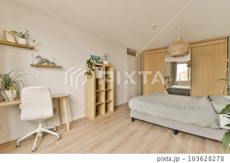 a bedroom with a bed, desk and shelves on the wall next to the bed is a white chair in front of it 103628278